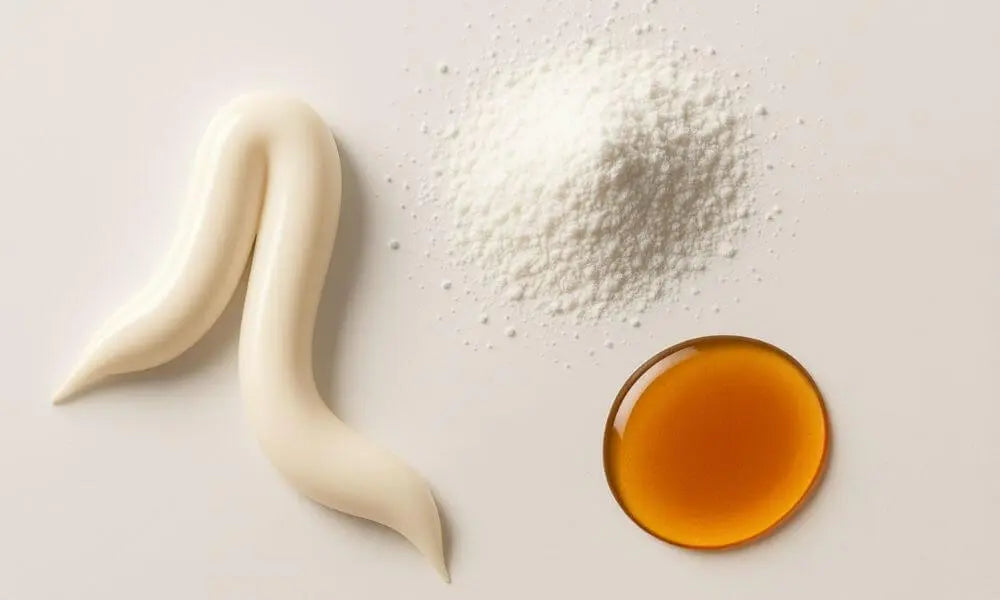 Three dental products on a light background: a squirt of toothpaste, a small pile of toothpowder, and a small pool of tooth oil.